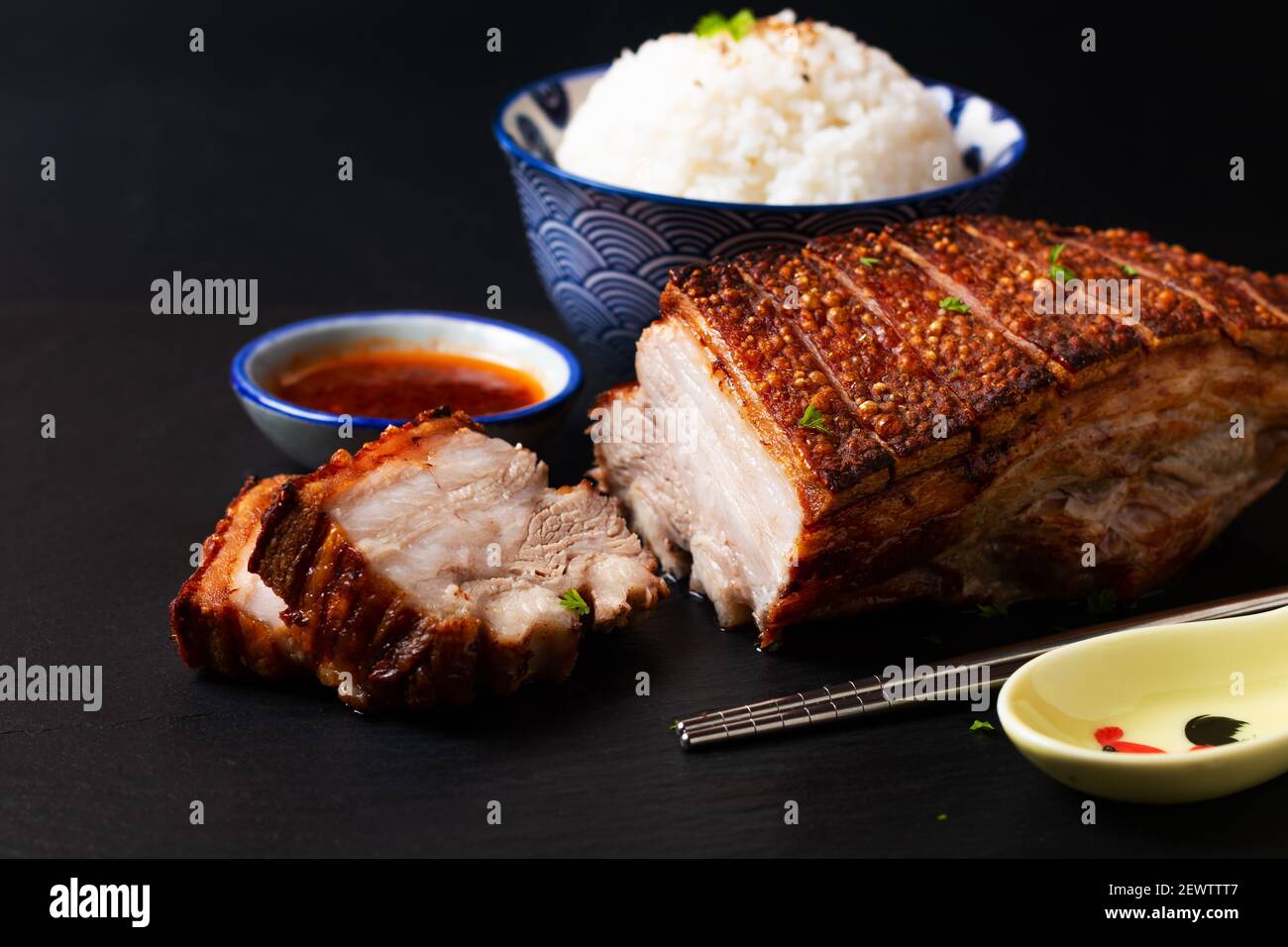 Il concetto di cibo focalizza la pancia di maiale croccante cotta in casa asse di pietra ardesia nero con spazio di copia Foto Stock