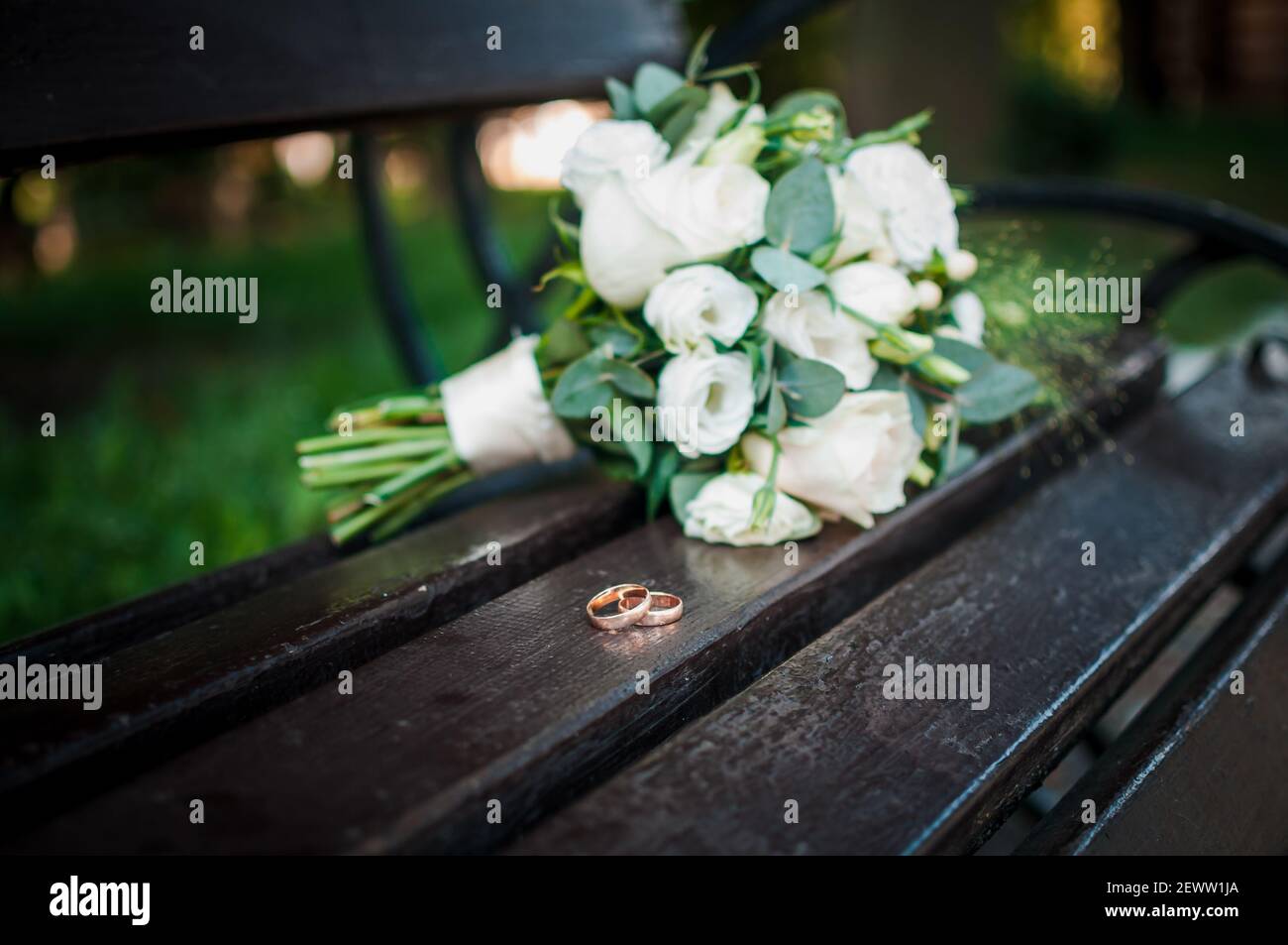 Gli anelli di nozze su un supporto di legno contro lo sfondo di il bouquet della sposa Foto Stock