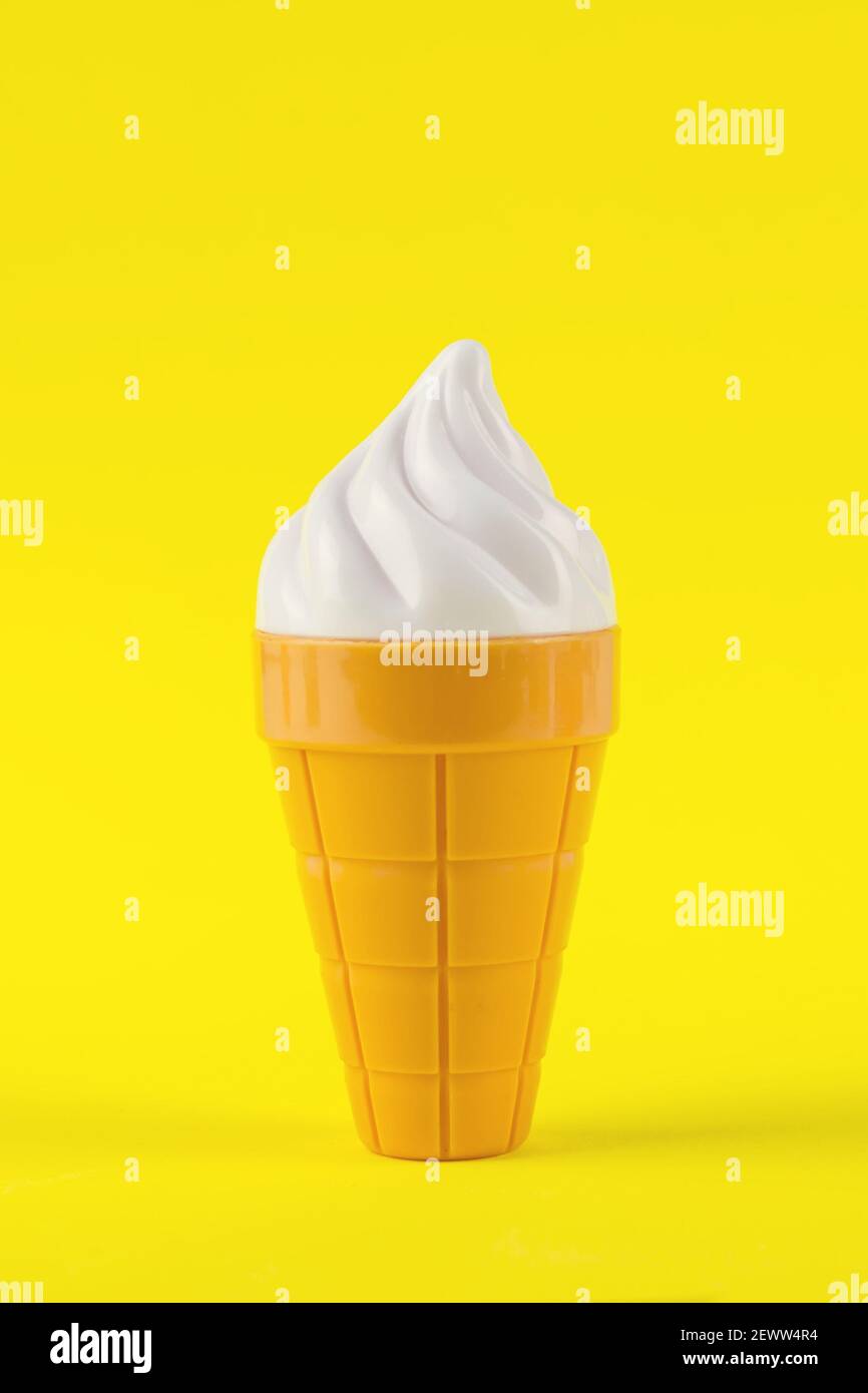 Gelato bianco nel cono del waffle con spazio per la copia sfondo giallo in stile minimal Foto Stock