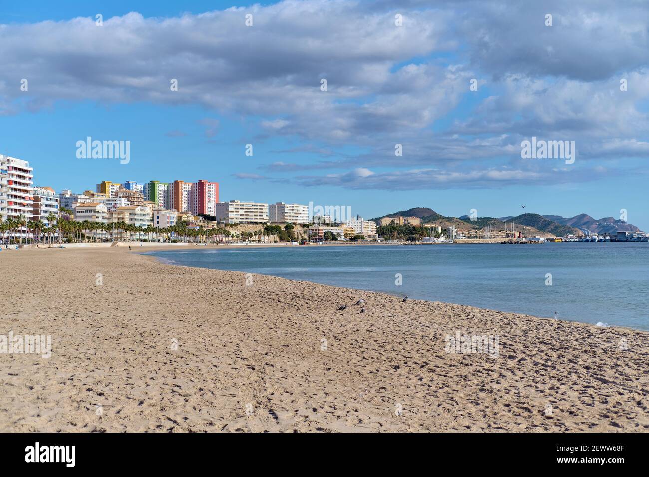 Vuota spiaggia di sabbia di Vila Joyosa o Villajoyosa città turistica skyline. Calmo Mar Mediterraneo durante la soleggiata calda giornata invernale. Viaggi e vacanze conce Foto Stock