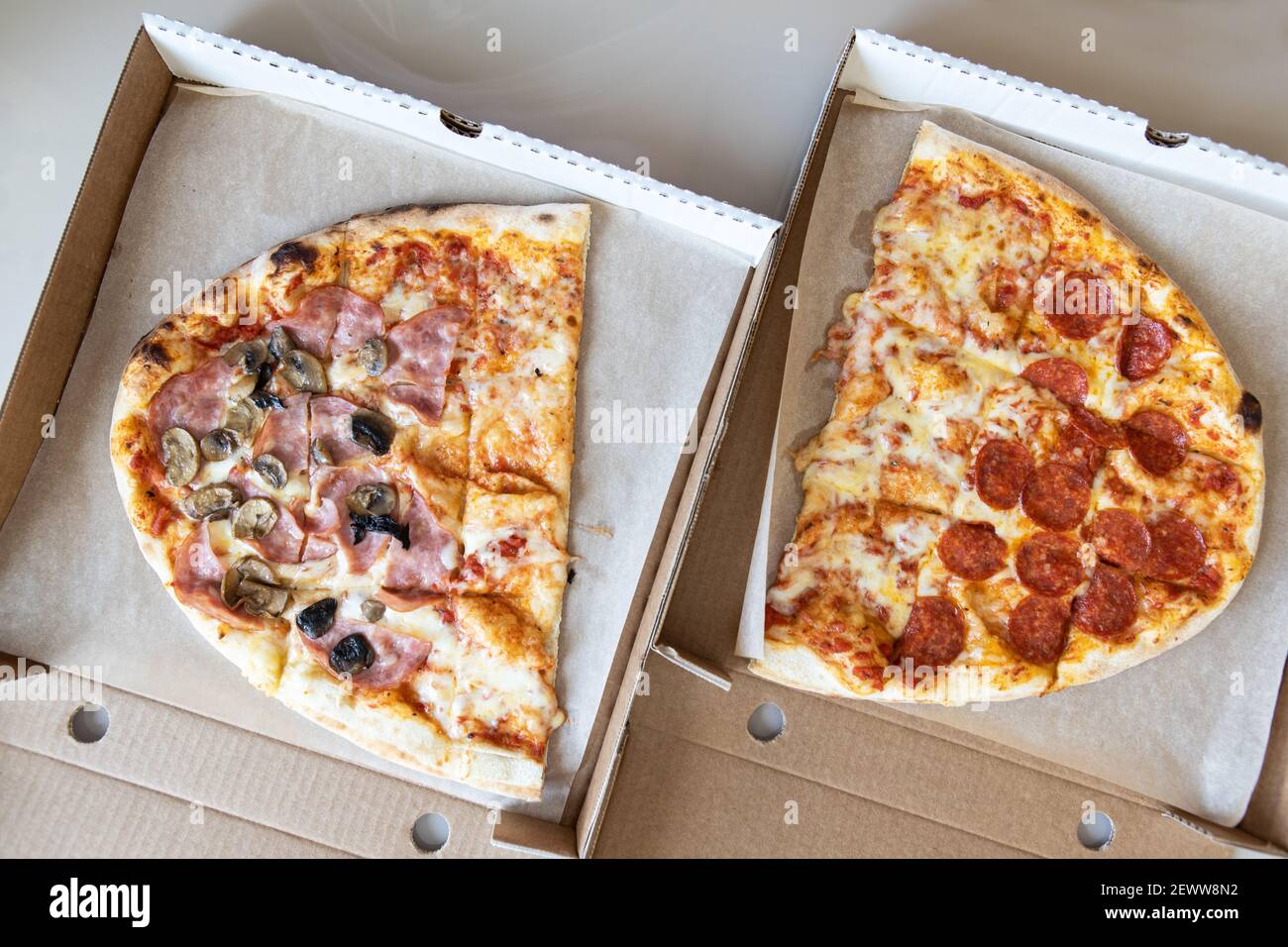 La pizza di famiglia, ovale, divisa in due metà, è composta da tre tipi: margarita, pepperoni, funghi prosciutto. Concetto di consegna di cibo, da asporto, italiano Foto Stock