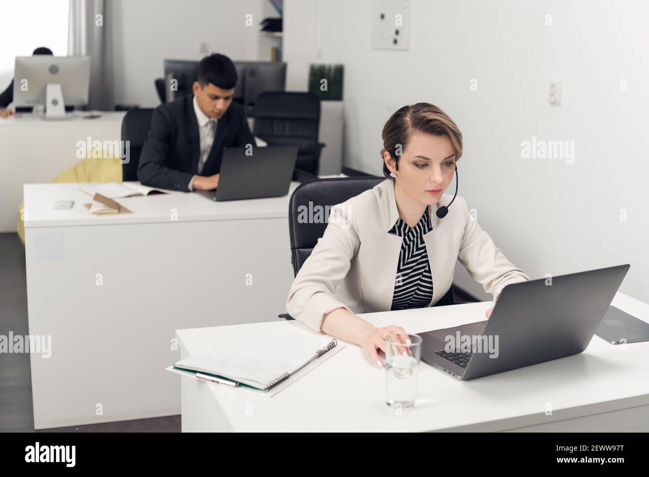 Una ragazza manager in ufficio in un abbigliamento da lavoro con un  computer portatile comunica con un cliente dell'azienda Foto stock - Alamy