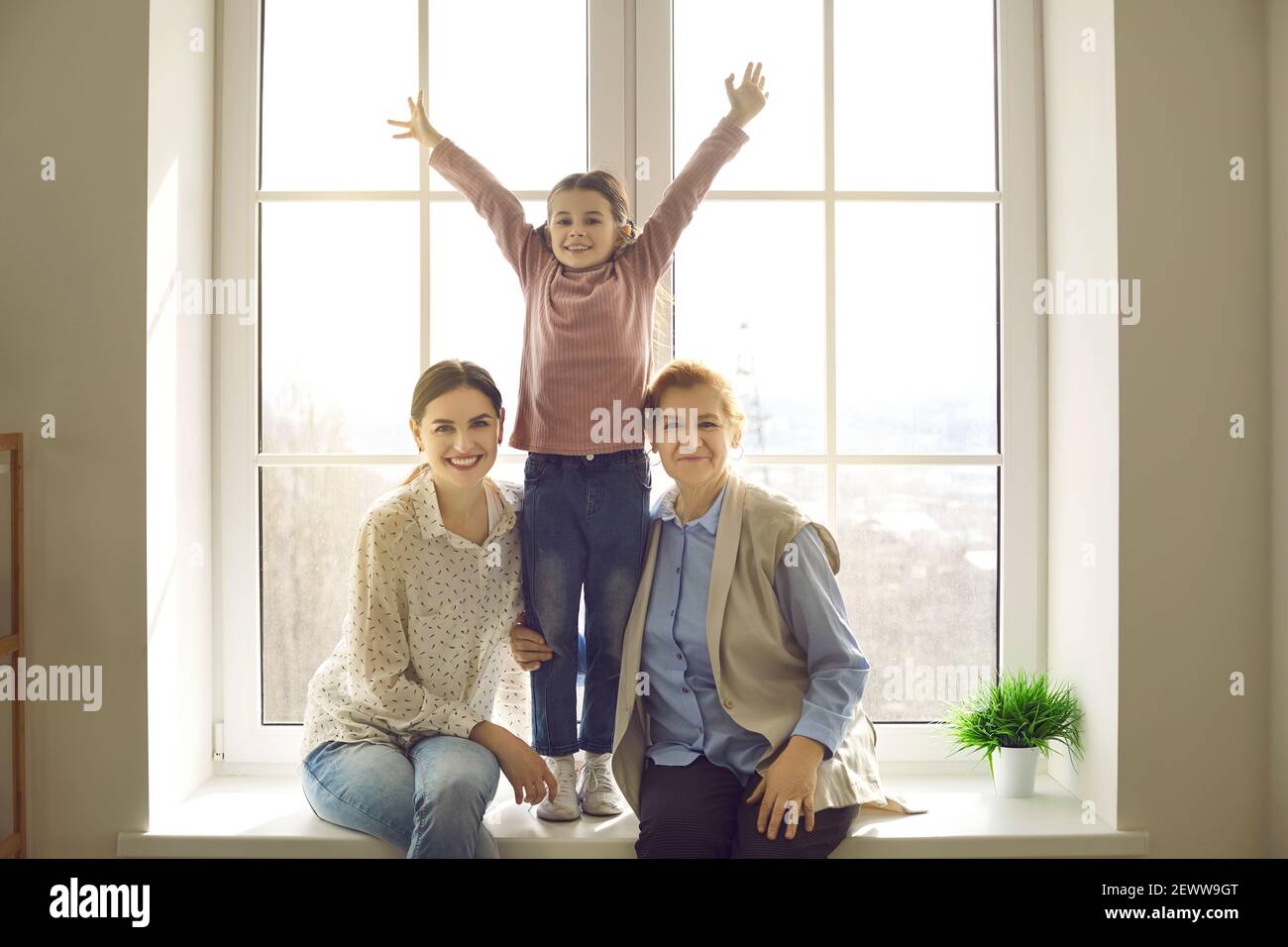 Ritratto di felice madre allegra, figlia e nonna sul davanzale a casa Foto Stock
