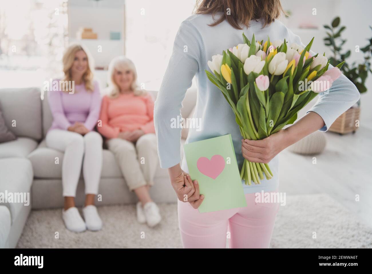 Rara vista foto di bambina che tiene tulipani cartolina mazzo nascondendosi dietro per congratularsi con la madre granny Foto Stock