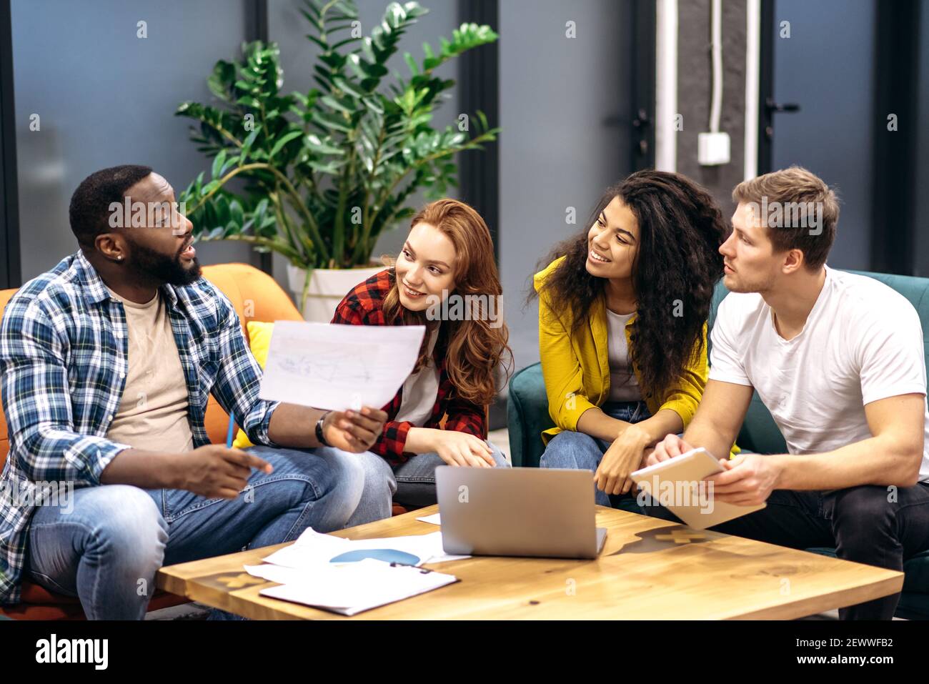 Team aziendale misto di successo, seduto in ufficio, parlando del processo di lavoro, sorridendo, comunicare tra loro, discutere di nuove startup, concetto di lavoro di squadra Foto Stock