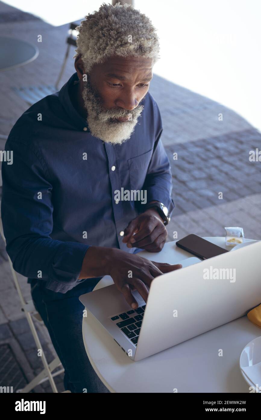 Uomo anziano afroamericano seduto al tavolo all'esterno del caffè computer portatile Foto Stock