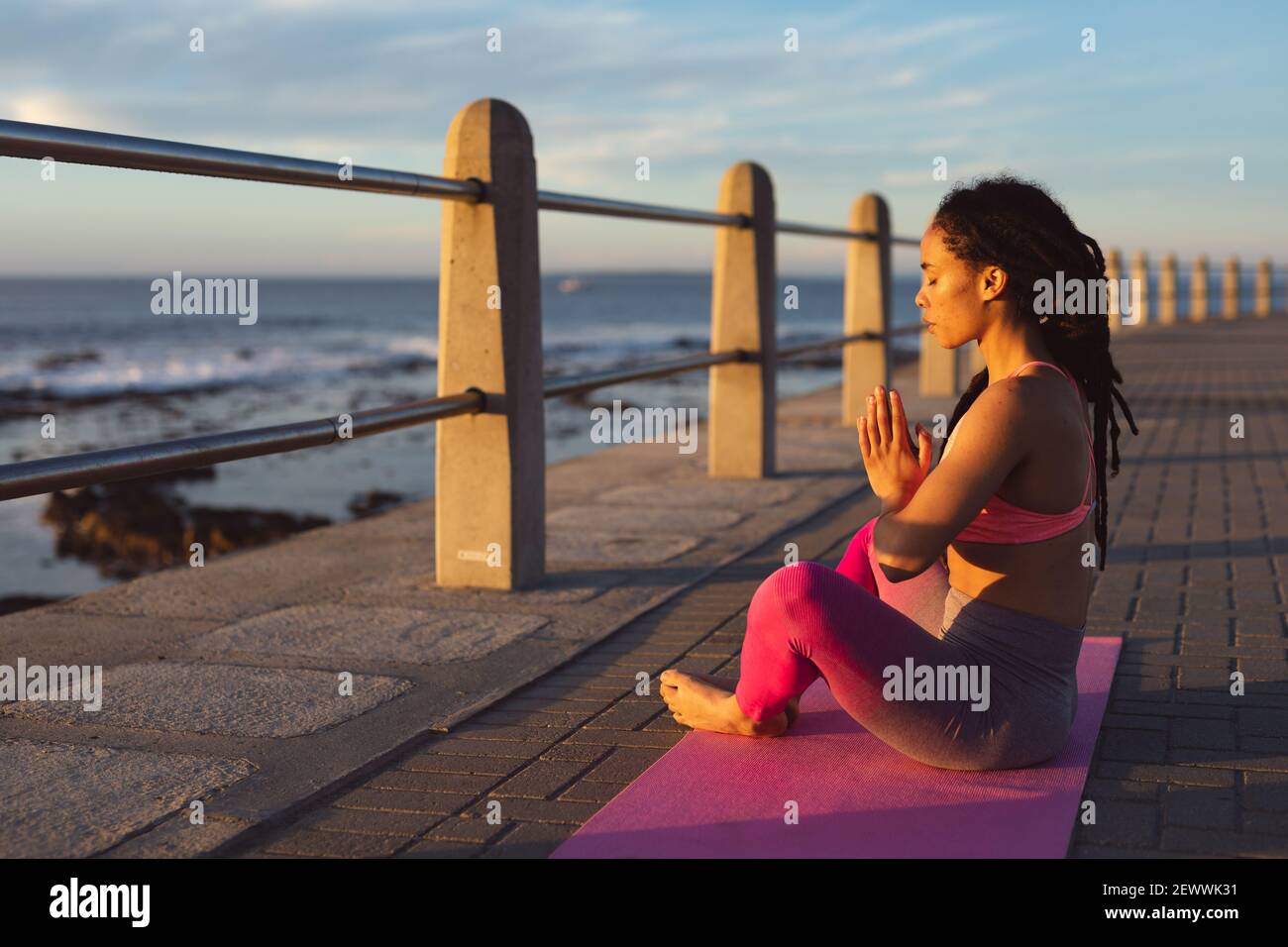 Donna afroamericana che si esercita sul lungomare dal mare facendo yoga Foto Stock