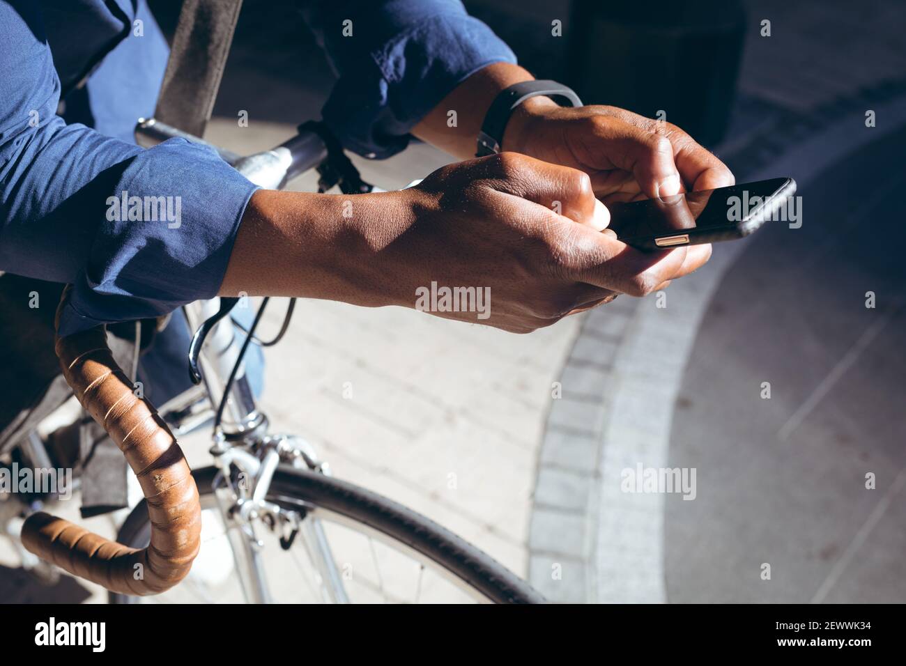 Sezione centrale dell'uomo anziano afro-americano che si appoggia sulla bicicletta via utilizzando lo smartphone Foto Stock