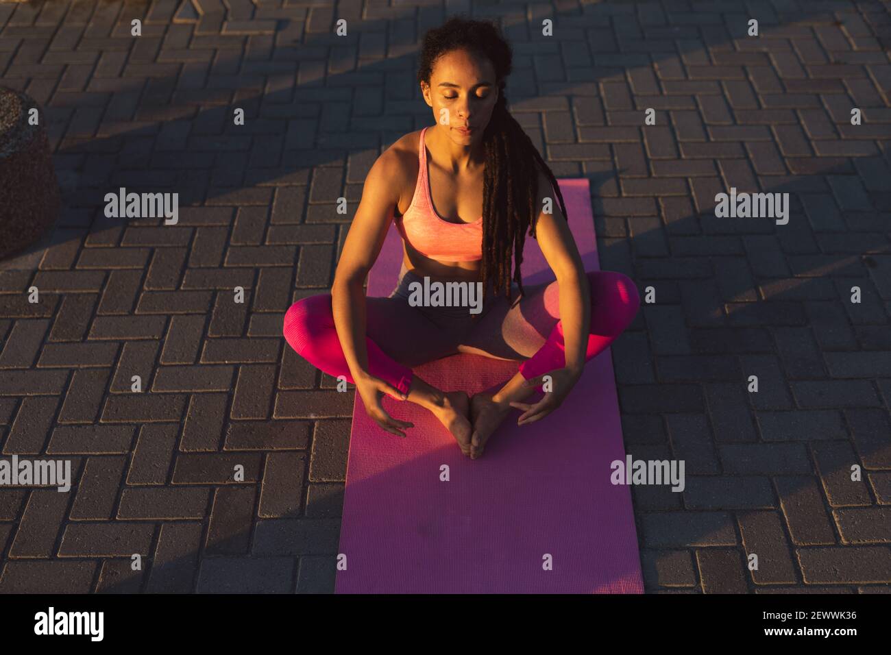 Donna afroamericana che si esercita sul lungomare dal mare facendo yoga Foto Stock