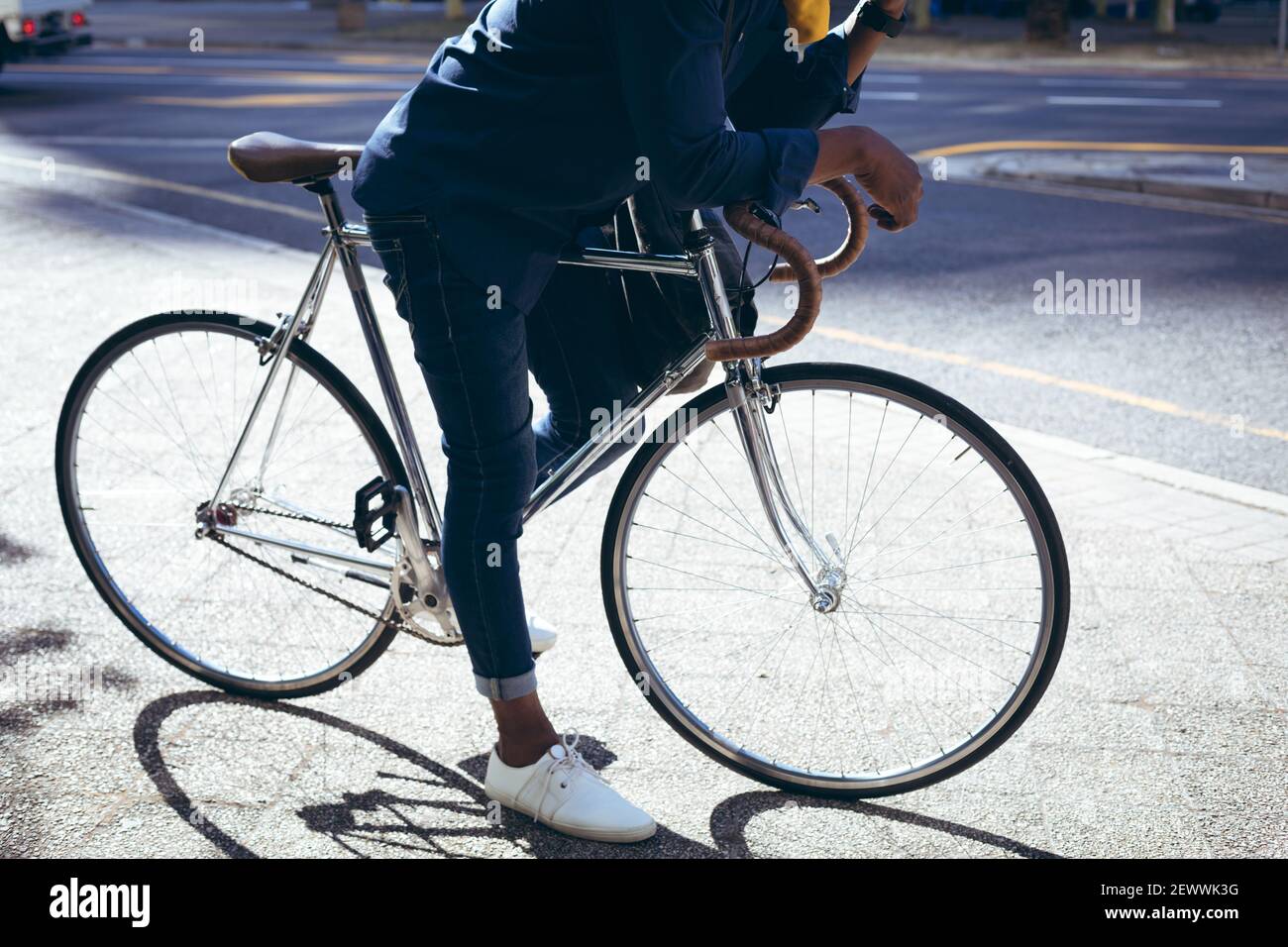 Sezione bassa dell'uomo anziano afroamericano che pende sulla bicicletta in strada che parla con lo smartphone Foto Stock