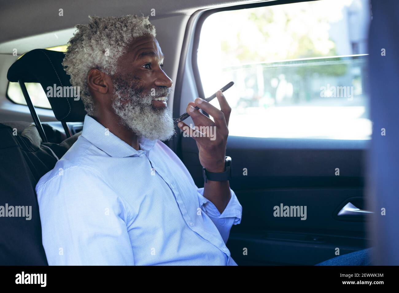 Uomo anziano afro-americano seduto in taxi che parla smartphone Foto Stock