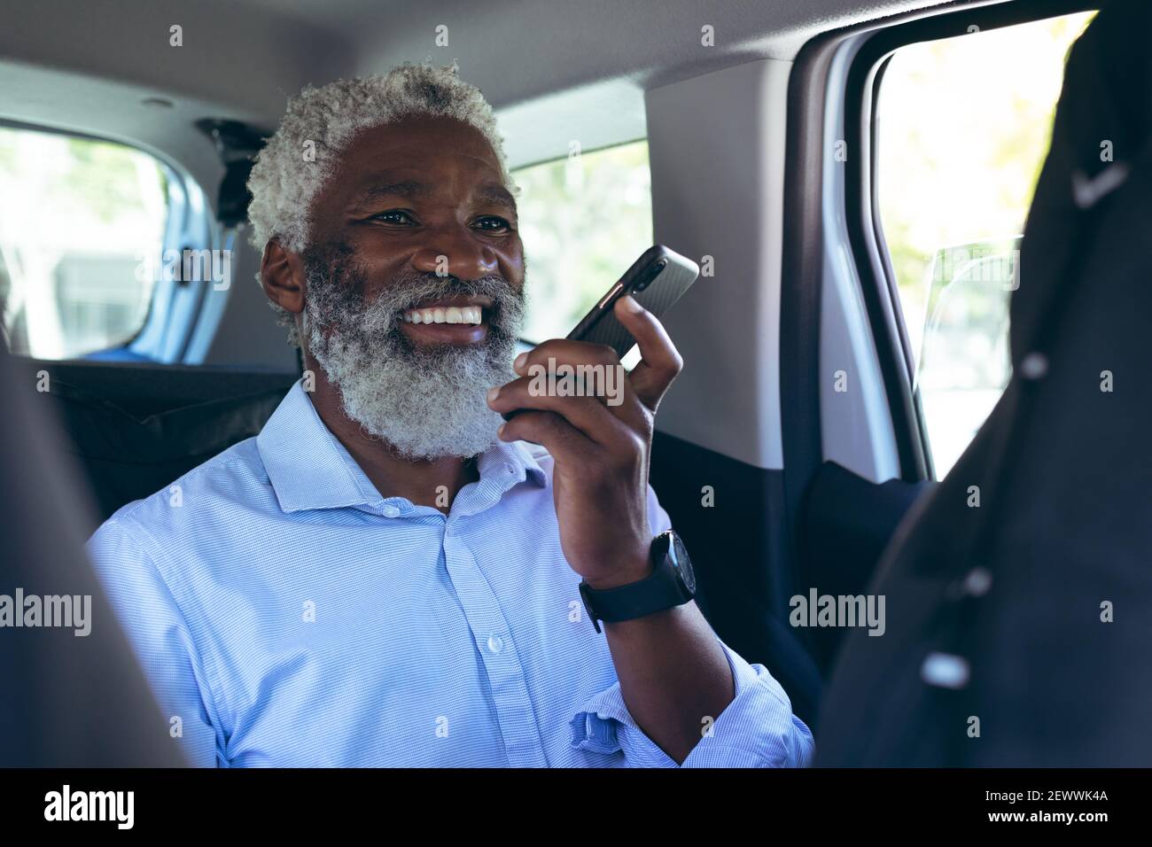 Uomo anziano afro-americano seduto in taxi che parla smartphone e sorridente Foto Stock