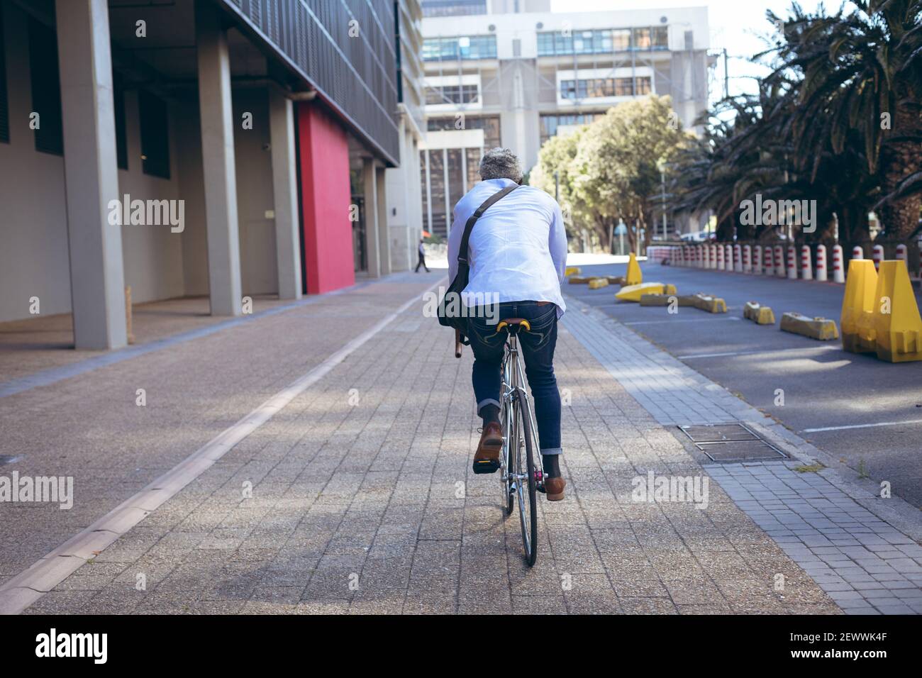 Vista posteriore di un uomo anziano afro-americano in bicicletta la strada Foto Stock