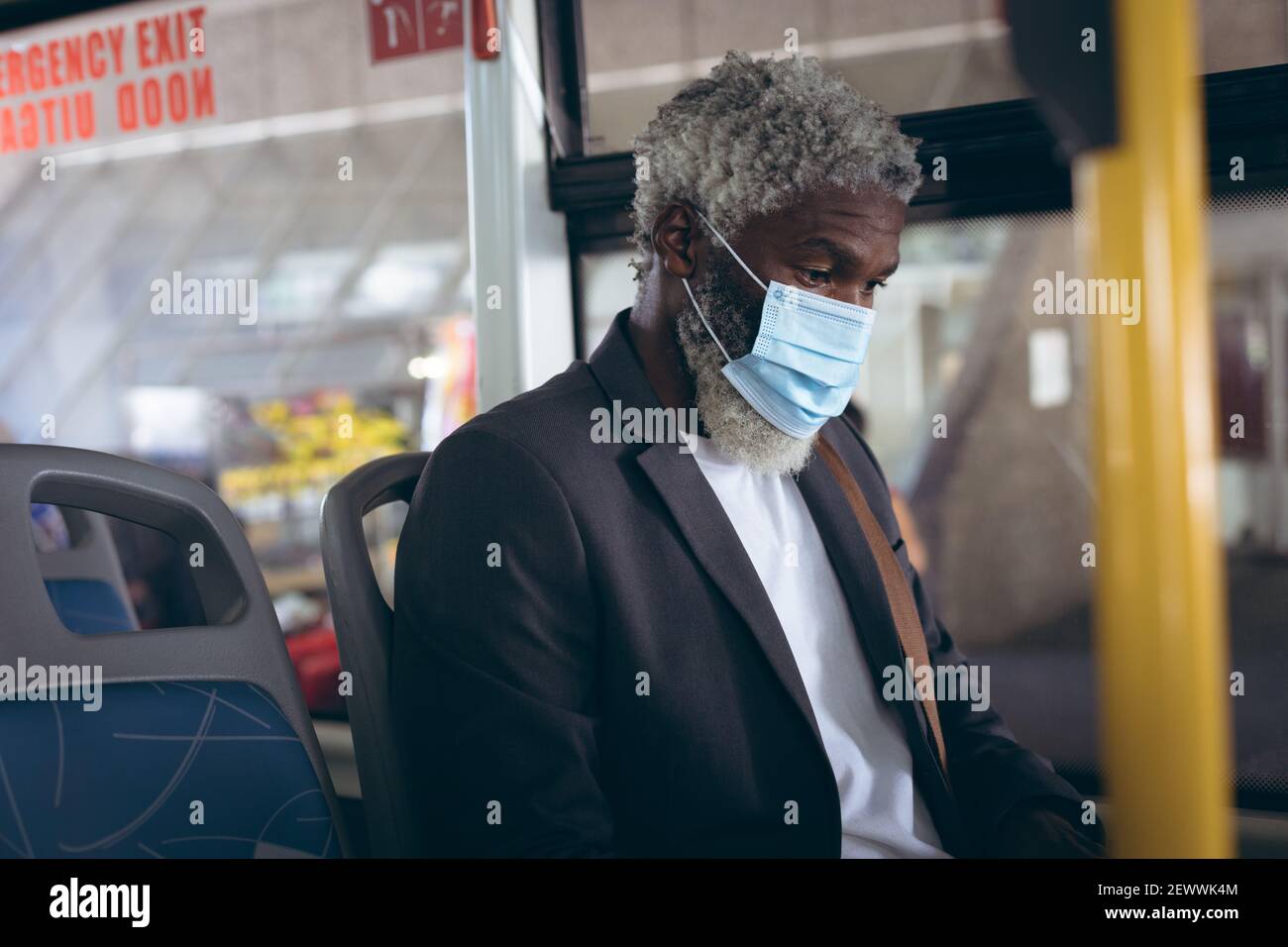 Uomo anziano afro-americano che indossa la maschera di faccia seduto sull'autobus Foto Stock