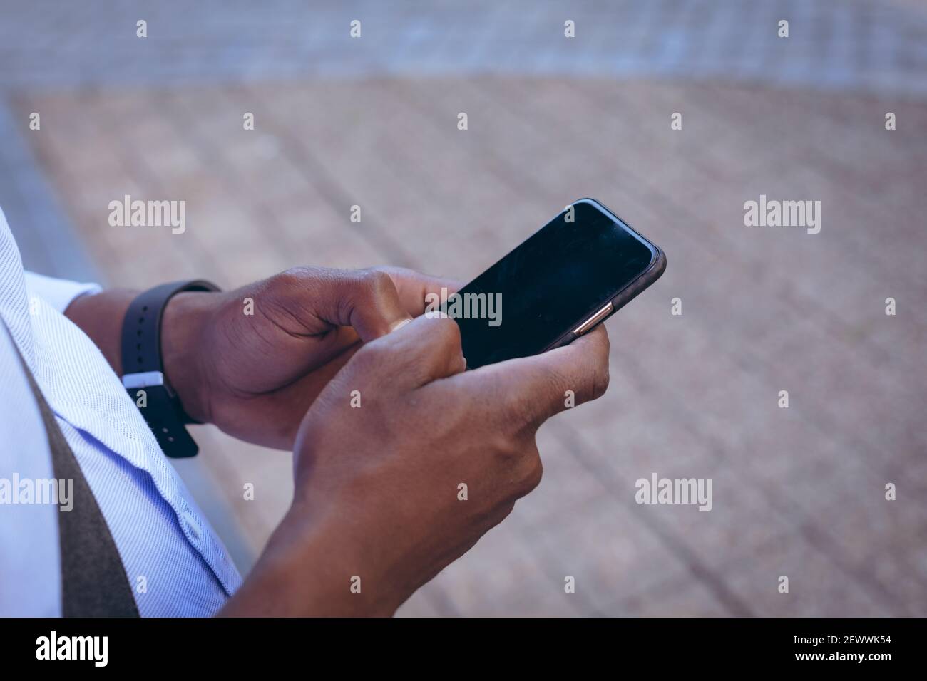 Sezione centrale dell'uomo afroamericano che sta nella strada usando smartphone Foto Stock