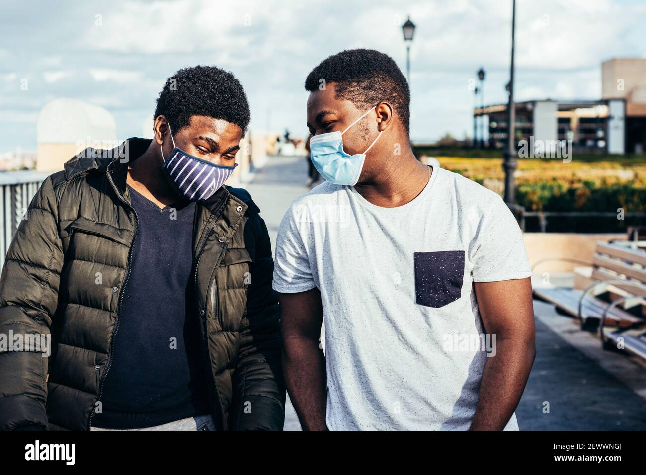 Ritratto di due amici afro-americani con maschera facciale che si divertono in uno spazio urbano. Foto Stock