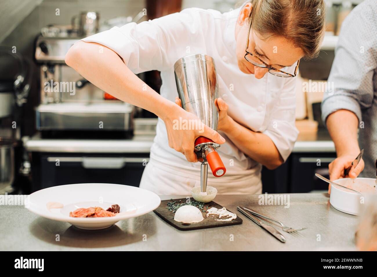 Chef prepara il cibo mentre lavora in cucina ristorante Foto Stock