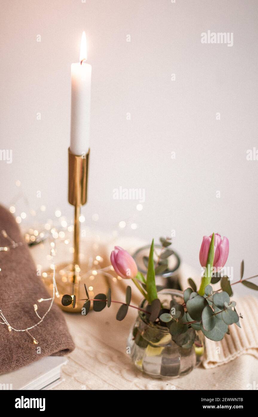 Angolo casa con libro, candela e fiori, closeup maglioni. Foto Stock