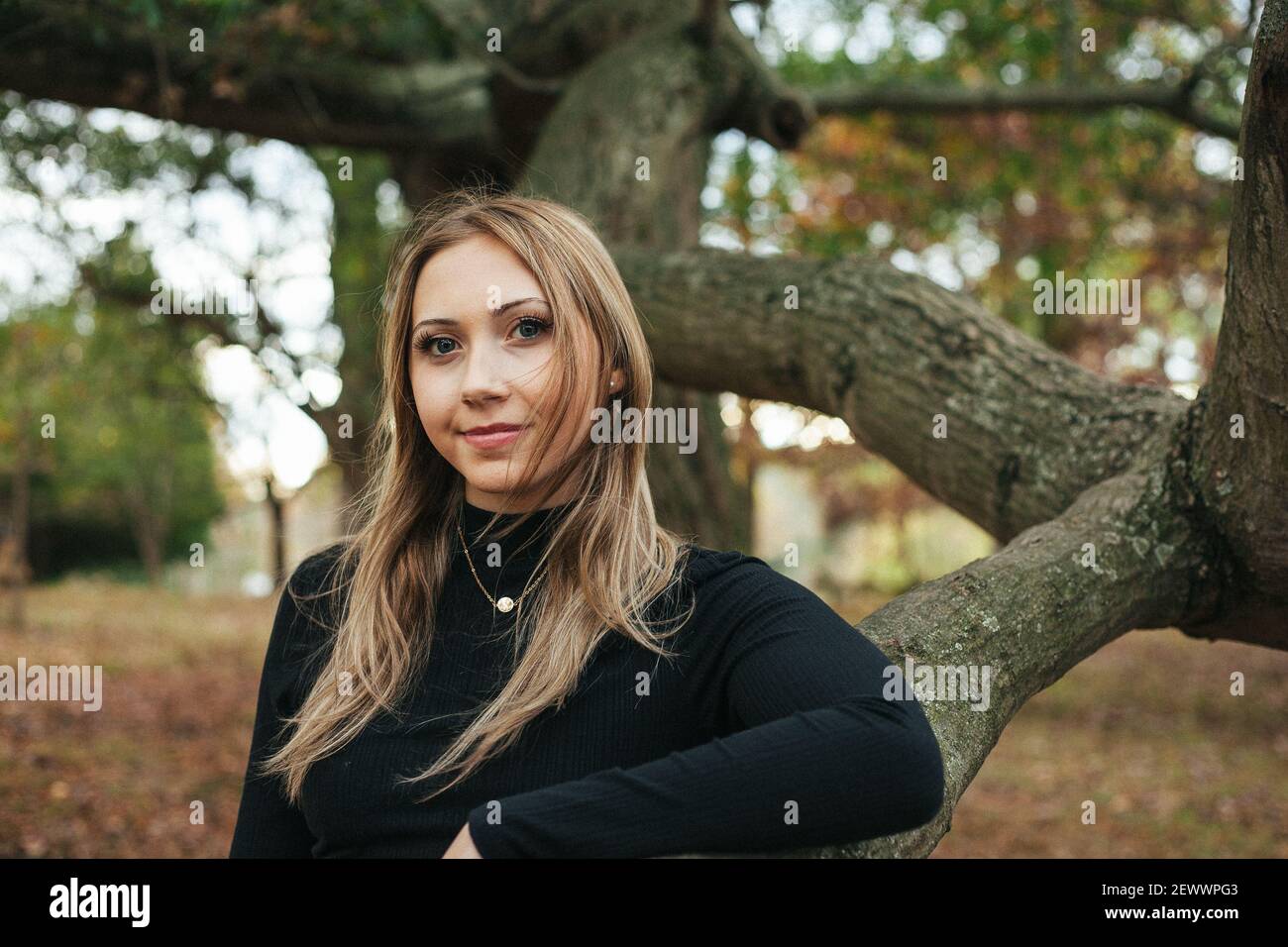 Una giovane donna si trova all'interno di un grande albero di quercia Un parco in Virginia Foto Stock
