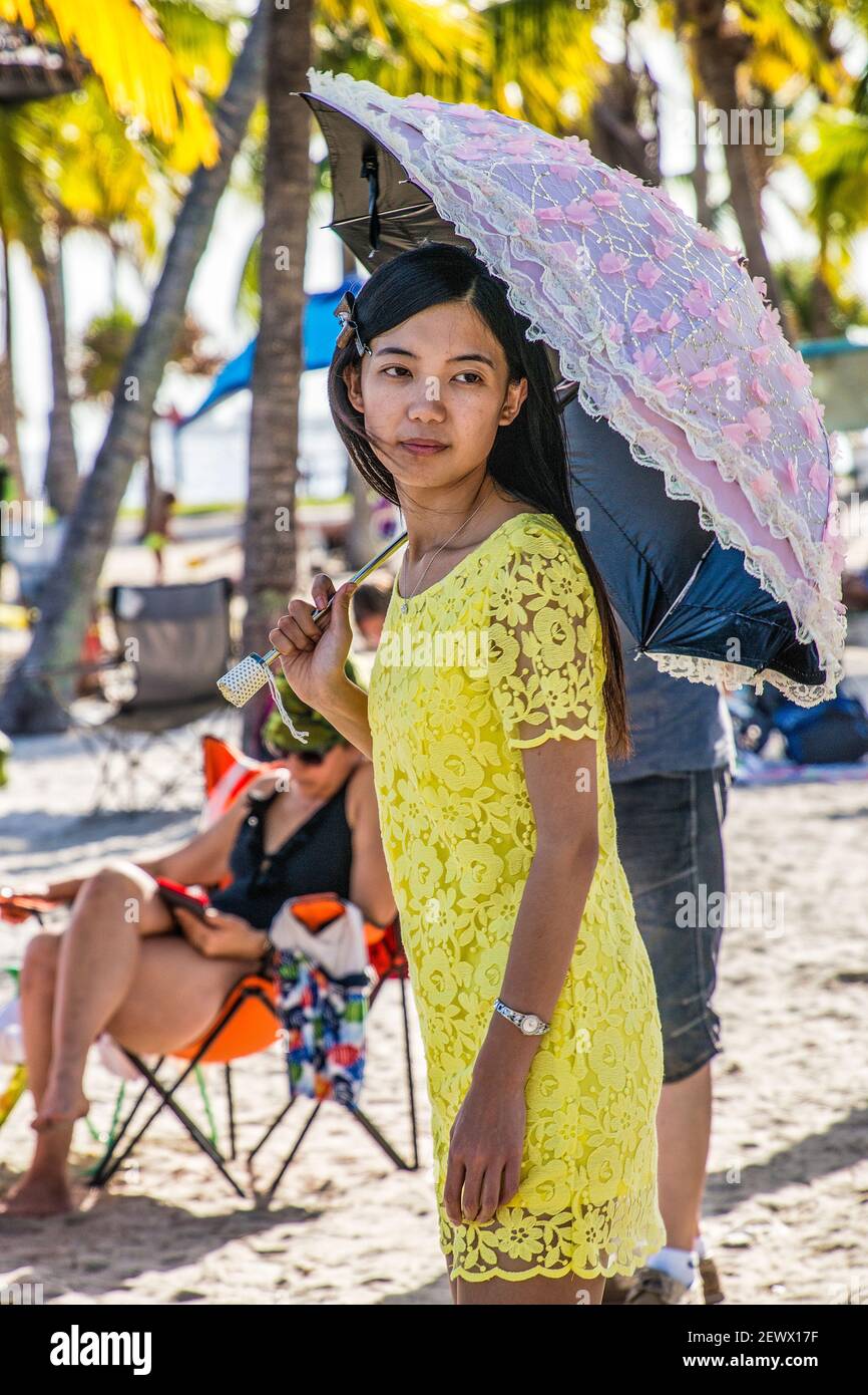 Una giovane donna con ombrellone si trova sulla spiaggia della piscina atollo di Matheson Hammock Park a Miami, Florida. Foto Stock
