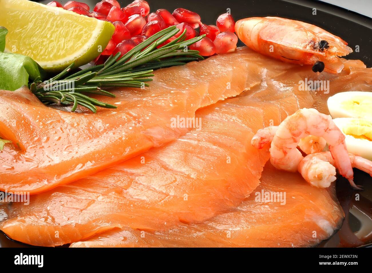 Appetitose fette di salmone affettato con gamberi al limone e melograno, cibo delizioso. Foto Stock