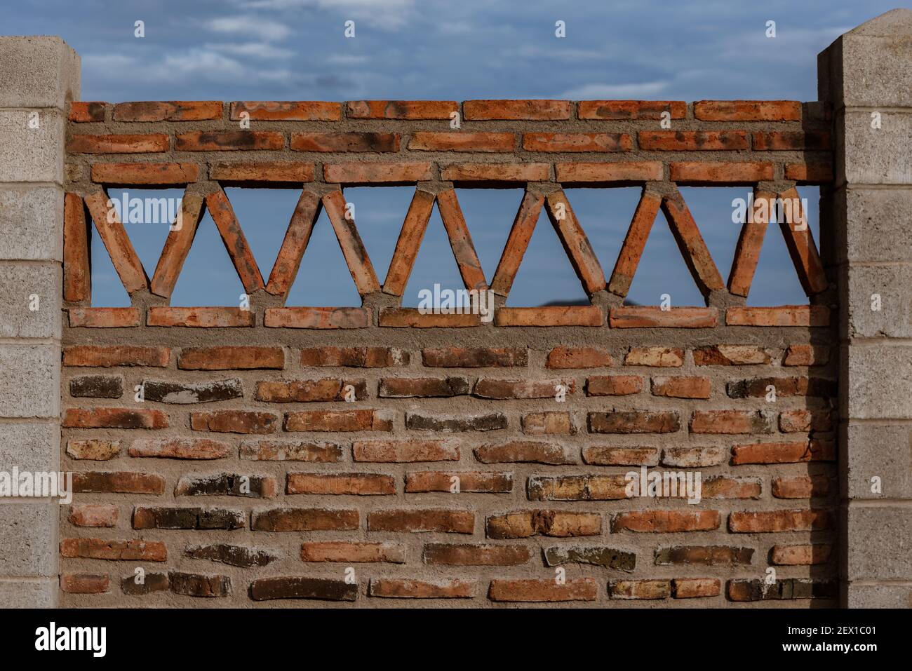 Una sezione di un muro di mattoni e scorie con una cima triangolare costruita per la privacy e la sicurezza di una residenza privata in Messico. Foto Stock
