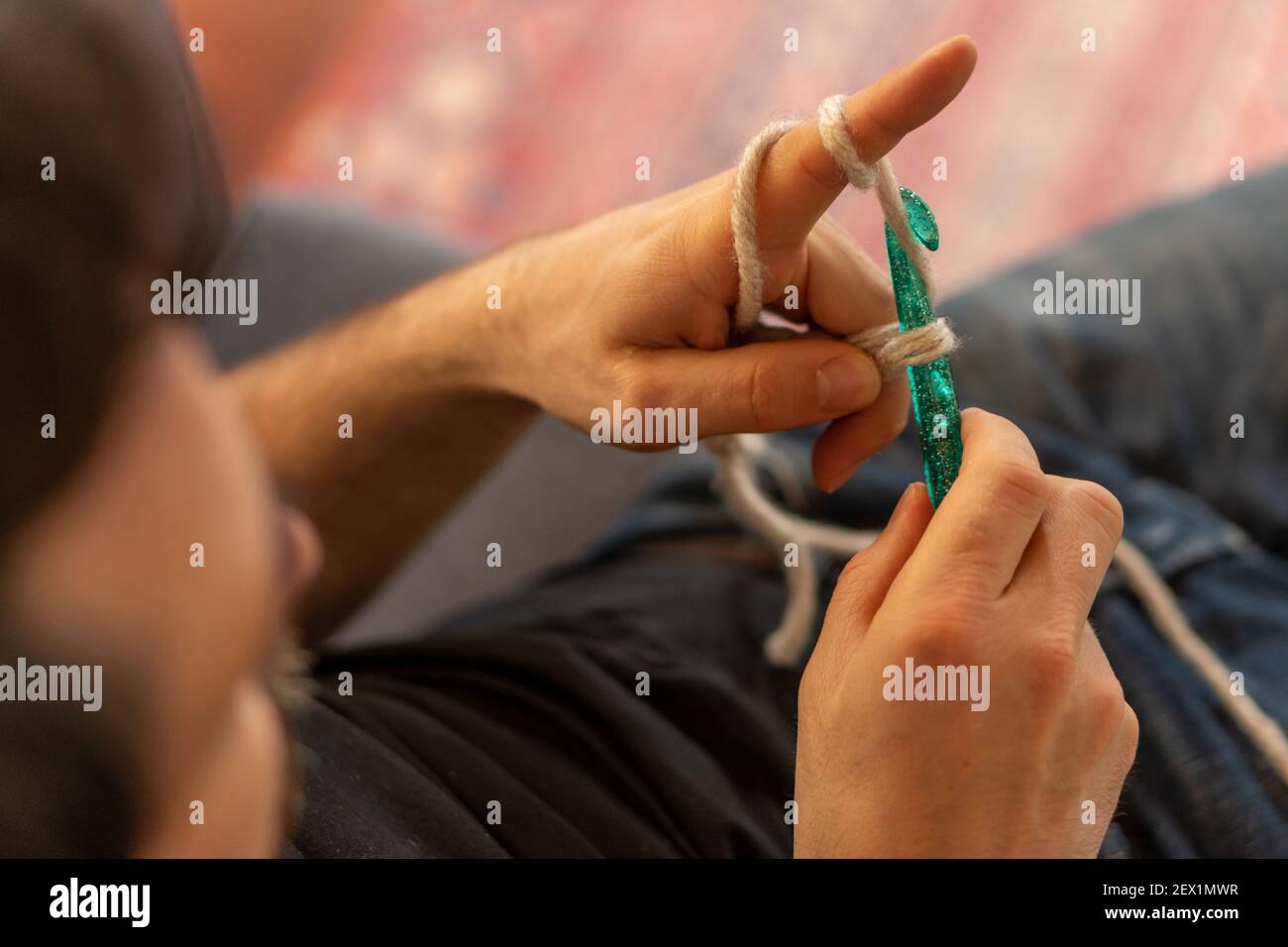 Mano dell'uomo con un grande e verde ago a crochet acrilico imparare un nuovo hobby Foto Stock