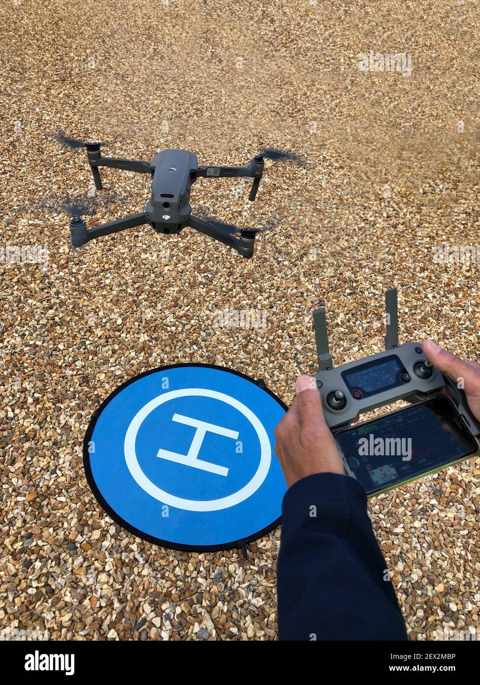 Operatore con comando e drone in volo con piazzola di atterraggio Foto Stock