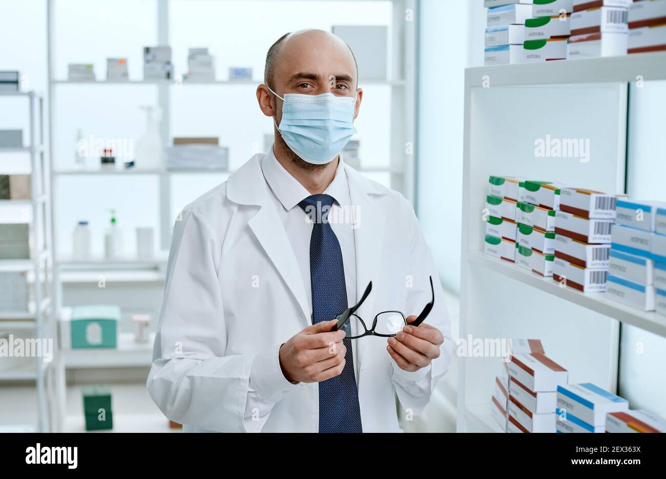 farmacista maschile in piedi vicino agli scaffali con farmaci . Foto Stock