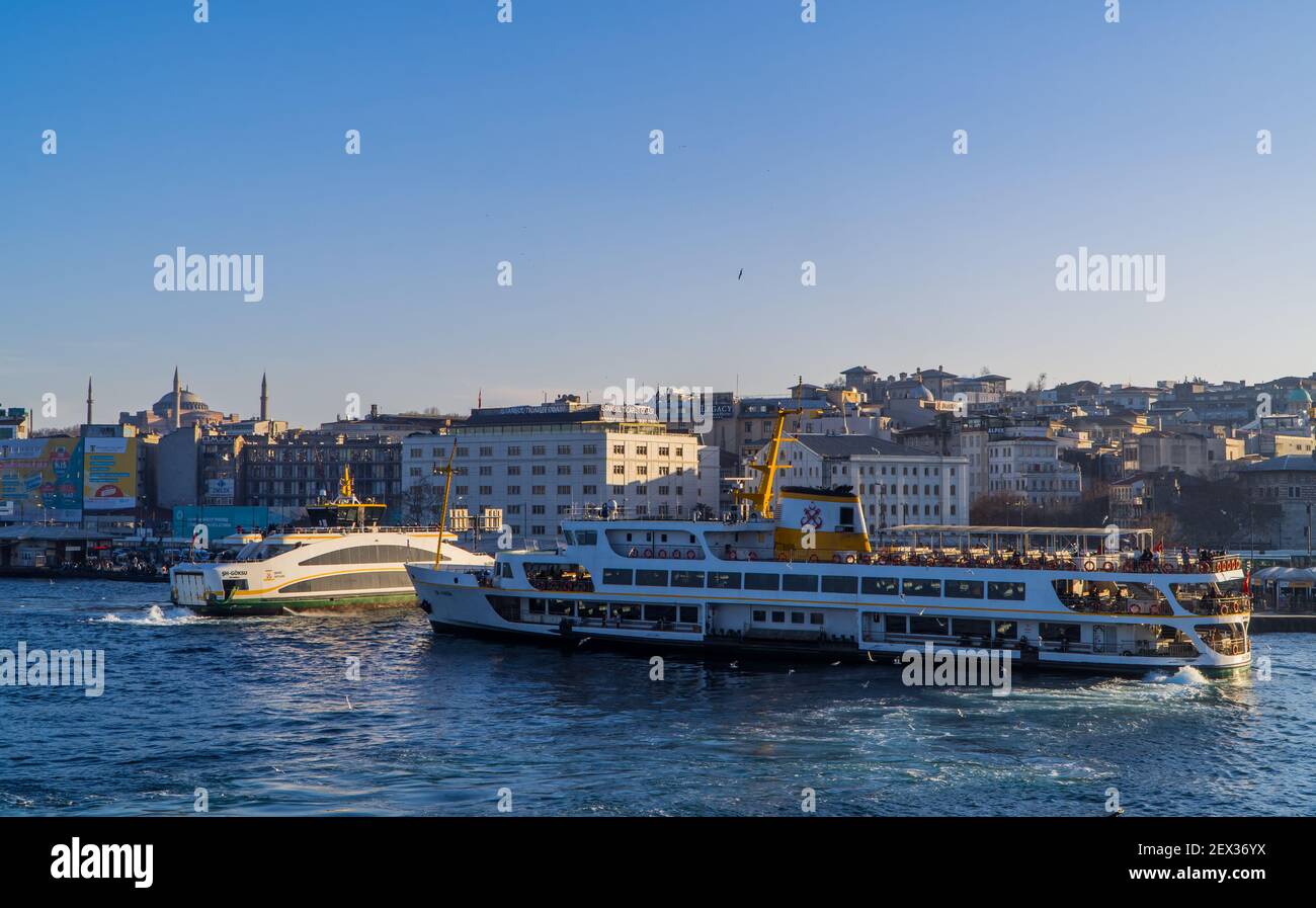 Istanbul, Turchia - 2 febbraio 2021 - splendida vista al tramonto dei moli di Eminönü con i traghetti e la Grande Moschea di Santa Sofia sulla collina Foto Stock