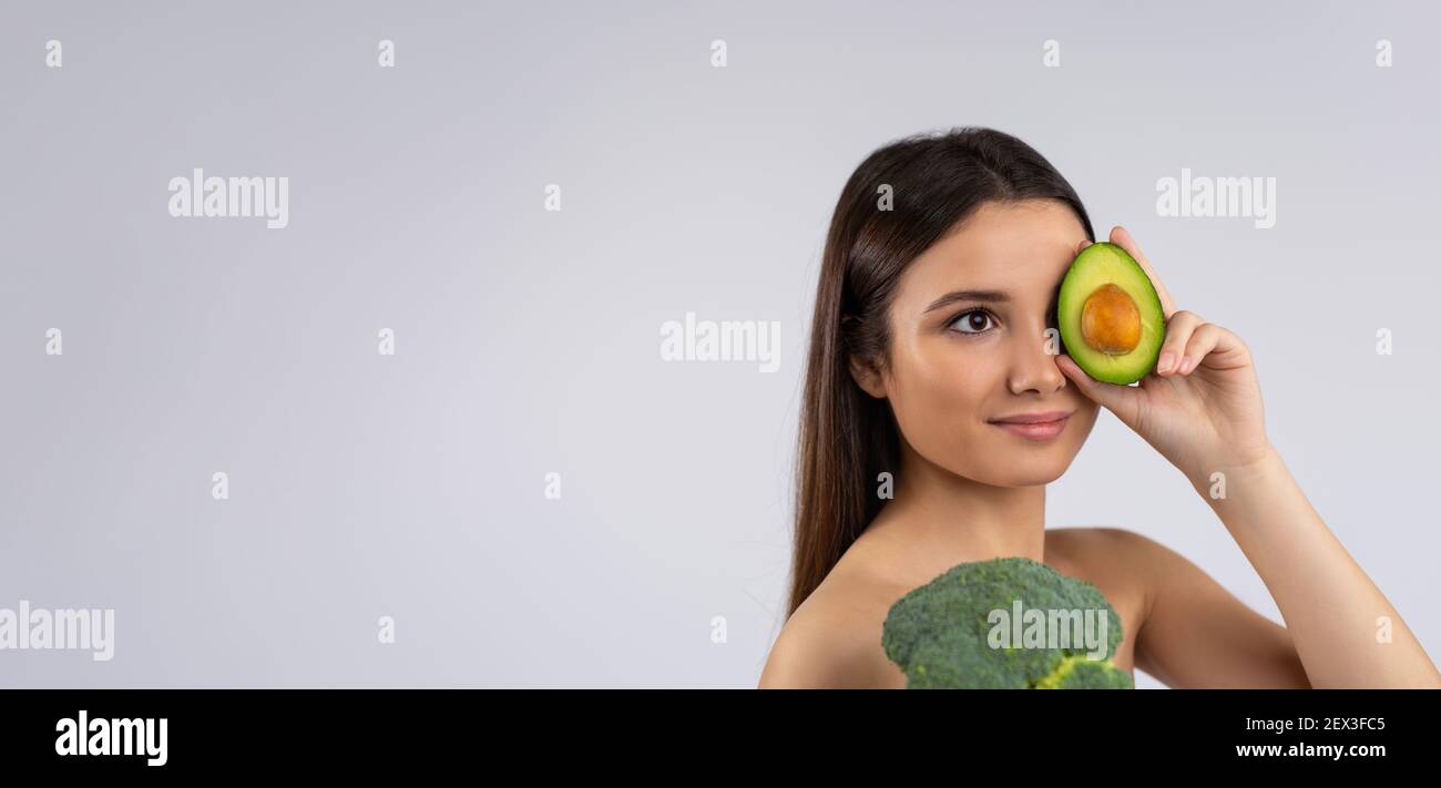 Banner - formato lungo. Vita verde, alimenti per una pelle sana e luminosa. Migliori prodotti anti-invecchiamento. Donna caucasica con pelle giovane e sbiadita che copre l'occhio Foto Stock