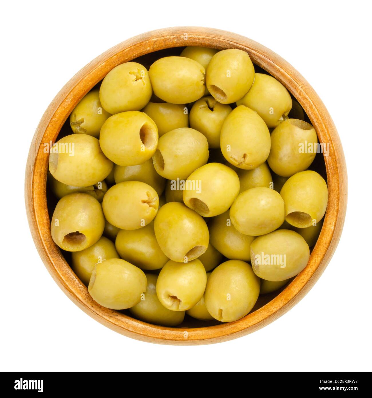 Piccole olive verdi da tavola in una ciotola di legno, sottaceto e snocciolate. Frutti verdi di Olea europaea, raccolti, stagionati e fermentati prima della conservazione. Foto Stock