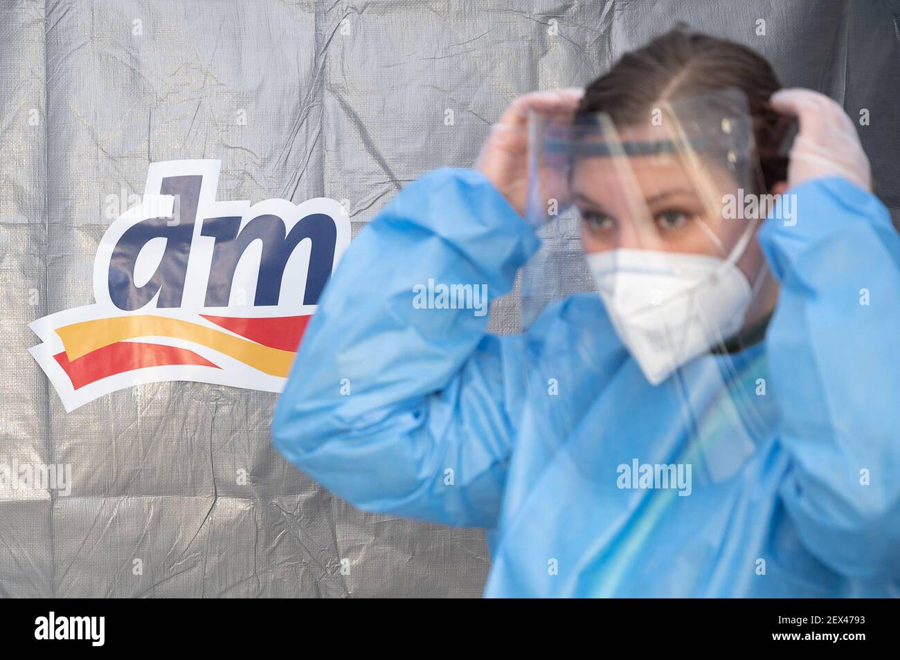 Karlsruhe, Germania. 04 marzo 2021. Un assistente medico mette sugli attrezzi protettivi durante la presentazione dei centri di test rapidi di Corona dalla catena di farmacia dm. La società ha proposto al governo dello stato di Baden-Württemberg di istituire centri di test rapidi Corona certificati presso i negozi dm dello stato. Credit: Sebastian Gollnow/dpa/Alamy Live News Foto Stock