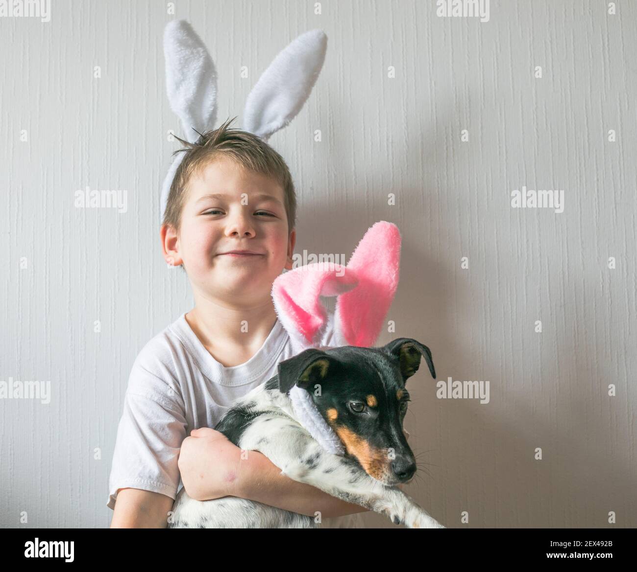 Piccolo ragazzo carino che indossa orecchie coniglietto pasquale, sorridi e  tiene il cane con orecchie coniglietto pasquale Foto stock - Alamy