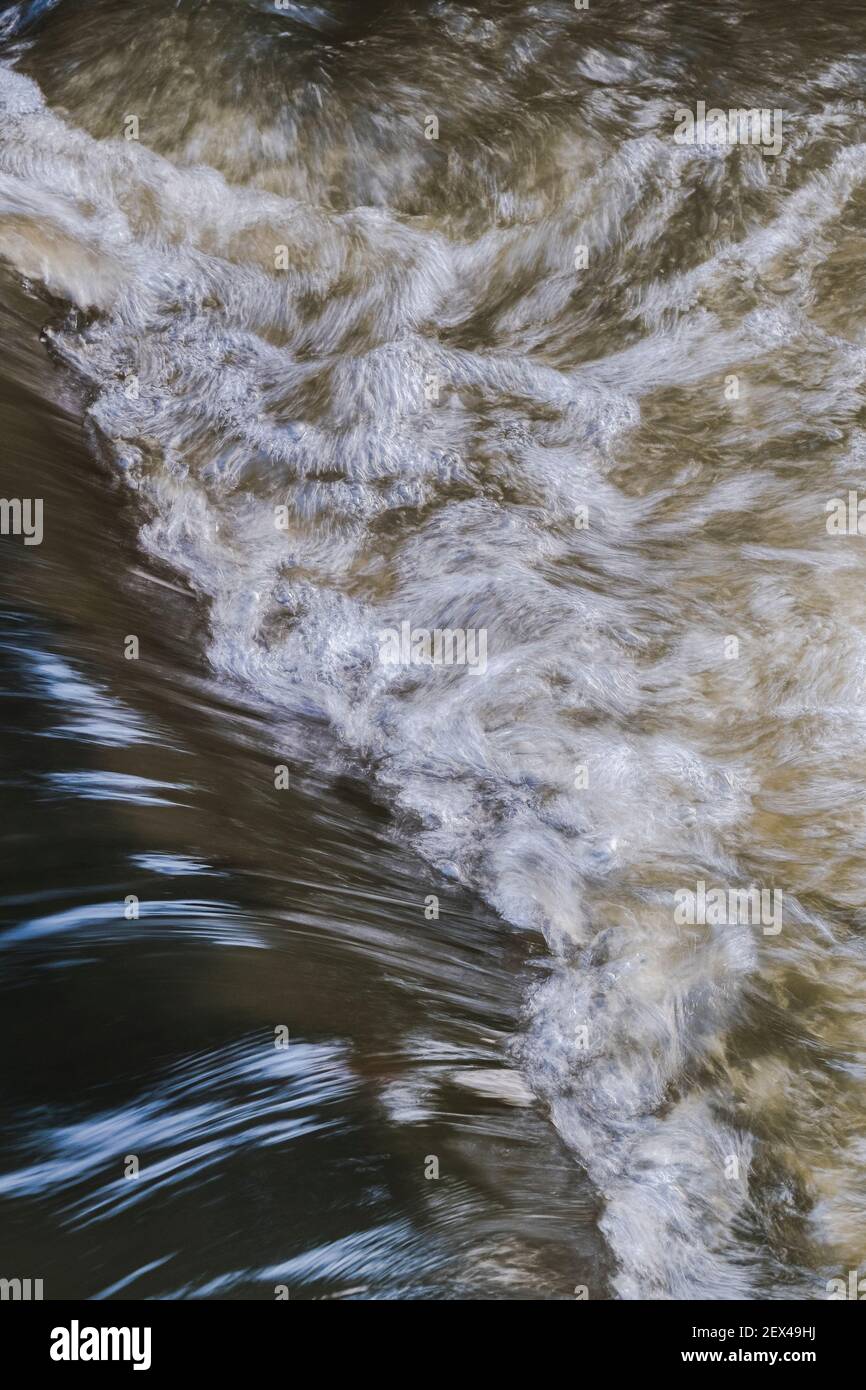 Acqua che vortola in fondo ad una piccola cascata in un ruscello. Foto Stock