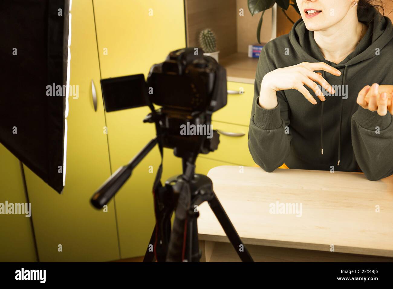 Una donna conduce una trasmissione vlog dal vivo, registra un video su una telecamera da casa. Comunicazione remota, nuova realtà, blog, videoconferenze Foto Stock
