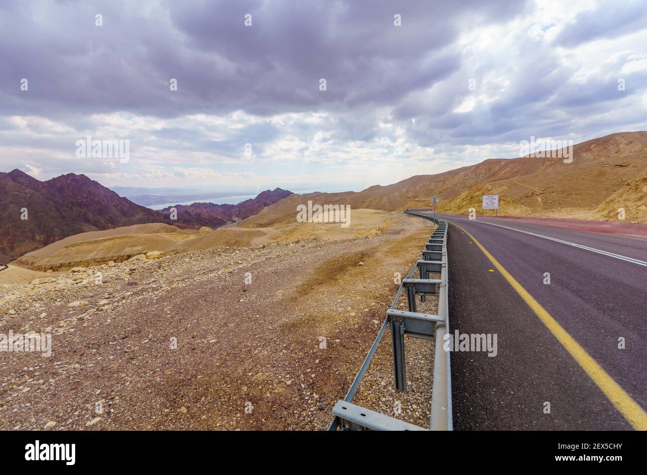 Vista della strada del deserto 12, con un segnale trilingue di avvertimento (curve pericolose) e paesaggio. Montagne di Eilat, Israele meridionale Foto Stock