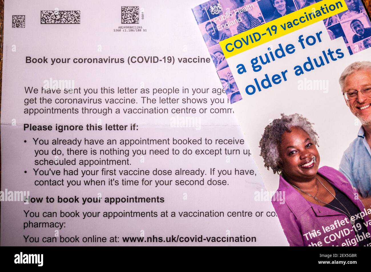 Lettera di invito del NHS per prenotare una vaccinazione con coronavirus per una persona di età superiore a 60 anni con foglio illustrativo. Ritoccato per rimuovere le informazioni personali. Foto Stock
