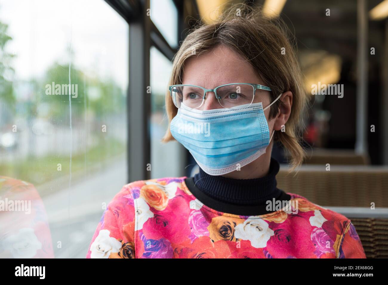 Attraente donna di trenta anni che indossa una maschera di bocca seduta Sul tram di Bruxelles durante le misure COVID Foto Stock