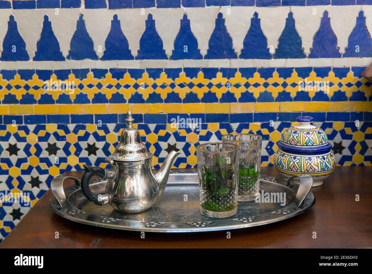 il tè alla menta viene servito su un vassoio d'argento contro un parete piastrellata Foto Stock
