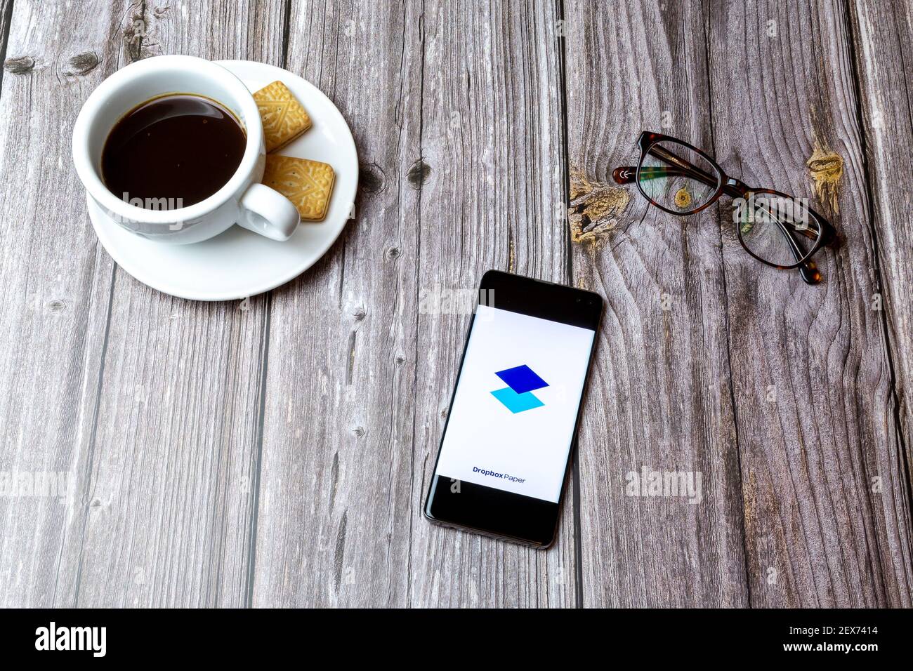 Un telefono cellulare o un telefono cellulare posato su un legno Tabella con l'applicazione carta Dropbox aperta accanto a caffè Foto Stock