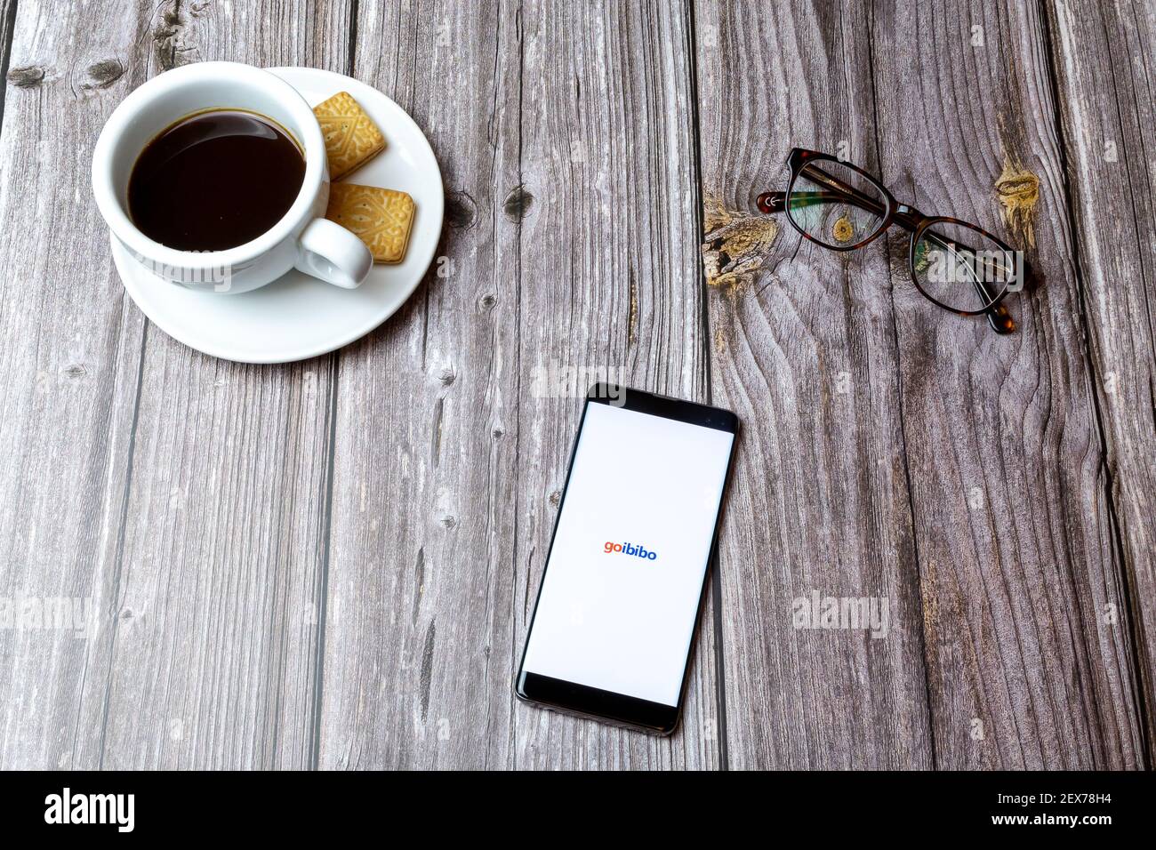 Un telefono cellulare o un telefono cellulare posato su un legno Tavolo con l'app Goibibo Travel aperta accanto a caffè Foto Stock