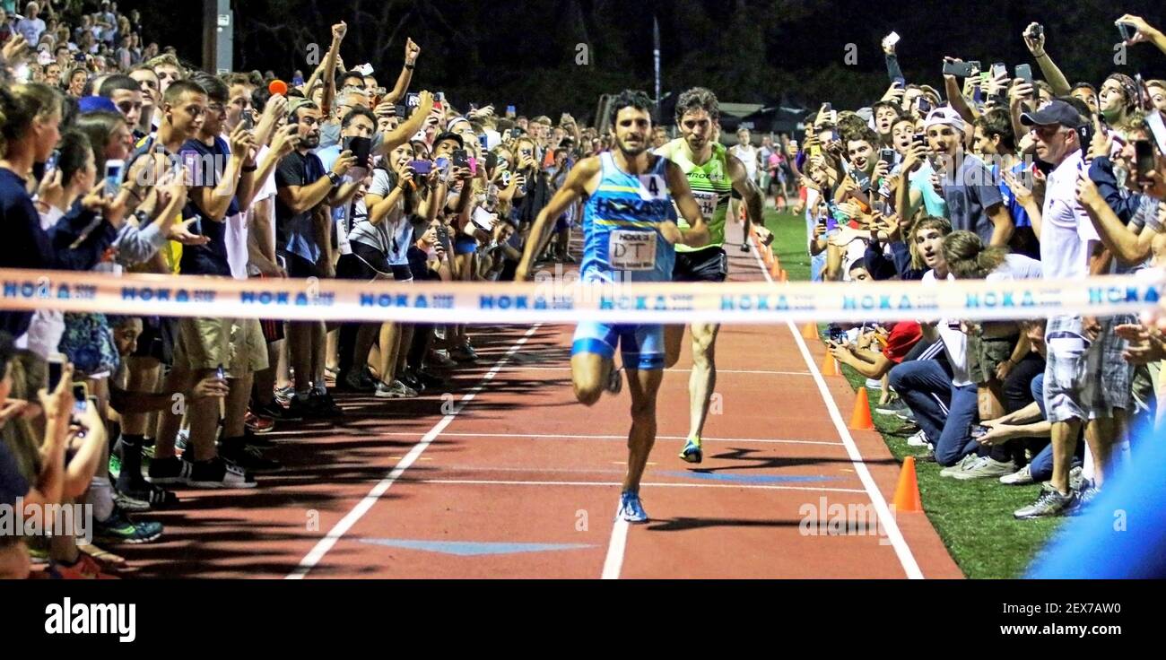 Huntington, New York, USA - 9 settembre 2015: Il corridore sta per bresk il nastro vincendo una gara con i tifosi che si acclamano e schierano la pista di notte. Foto Stock