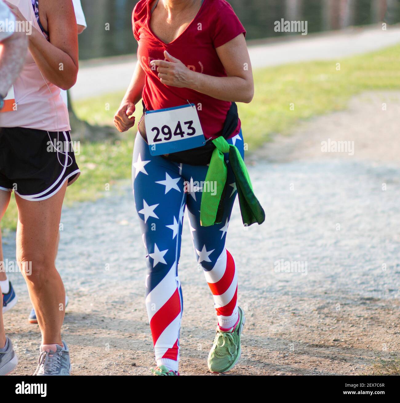 Una corridore femminile indossa spandex bandiera americana mentre corre una corsa 5K intorno ad un lago. Foto Stock