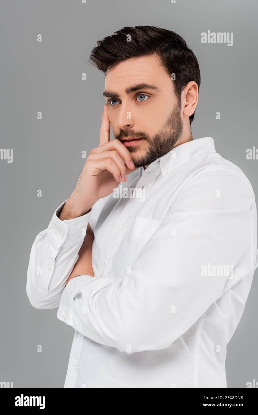 Giovane uomo bearded in camicia bianca isolato su grigio Foto Stock