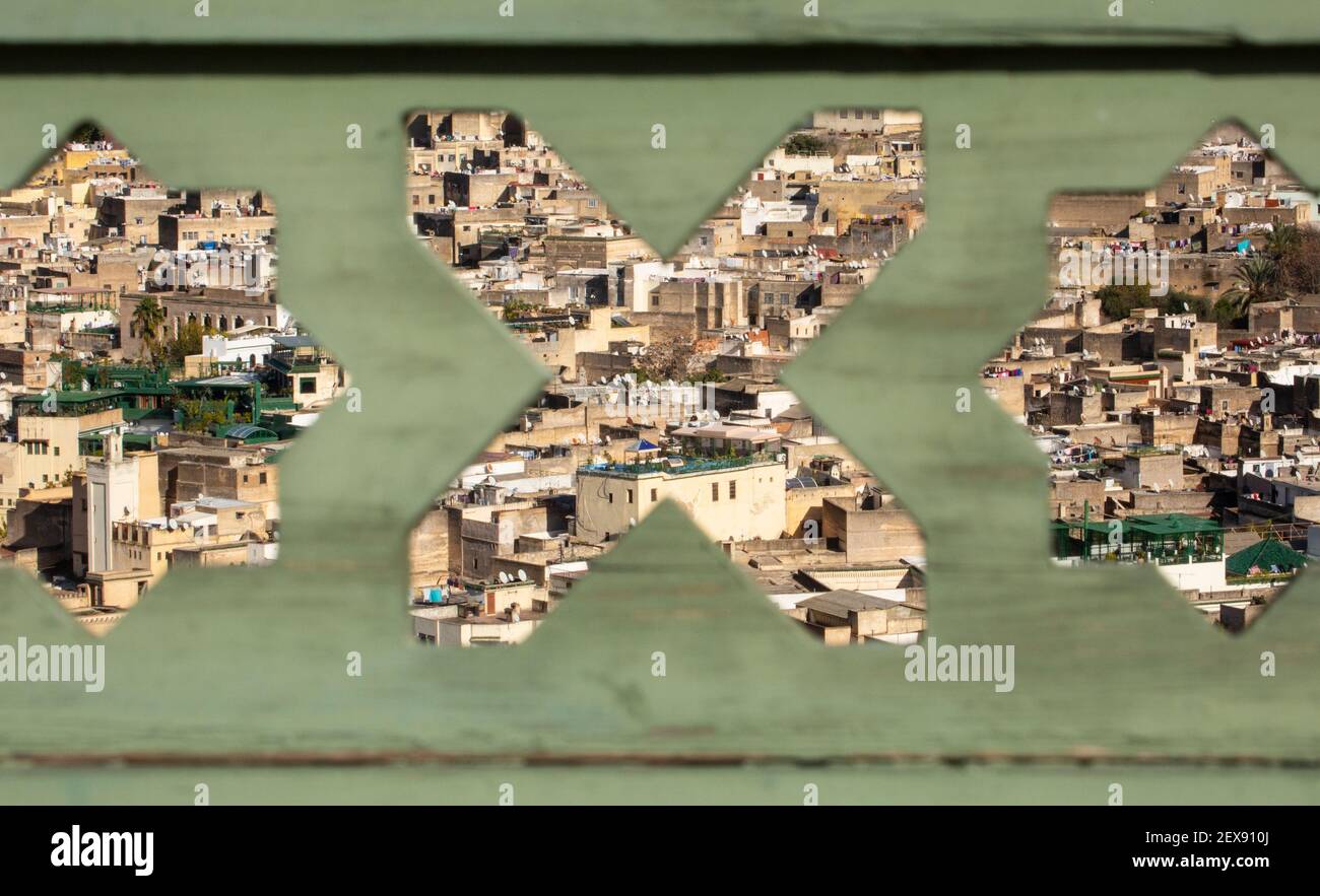 Vista dal paesaggio urbano dei tetti della medina Fes attraverso intagli decorativi a forma di stella su una recinzione sulla terrazza del Palais Faraj, Fes, Marocco Foto Stock