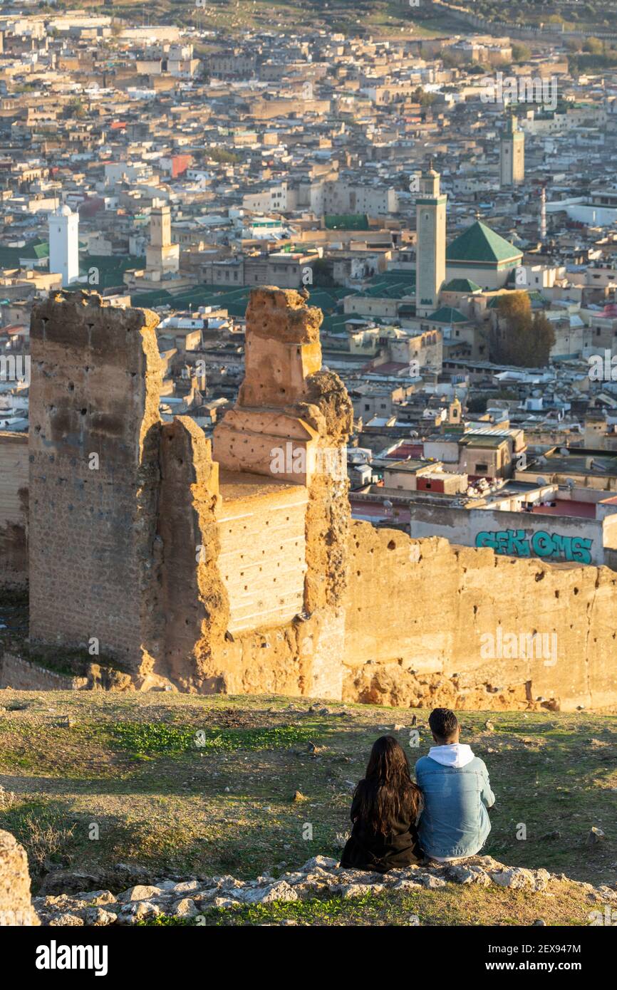 Una giovane coppia locale vi godrete un tramonto che si affaccia sulla medina di Fes dalle Tombe Marinide, Fes, Marocco Foto Stock