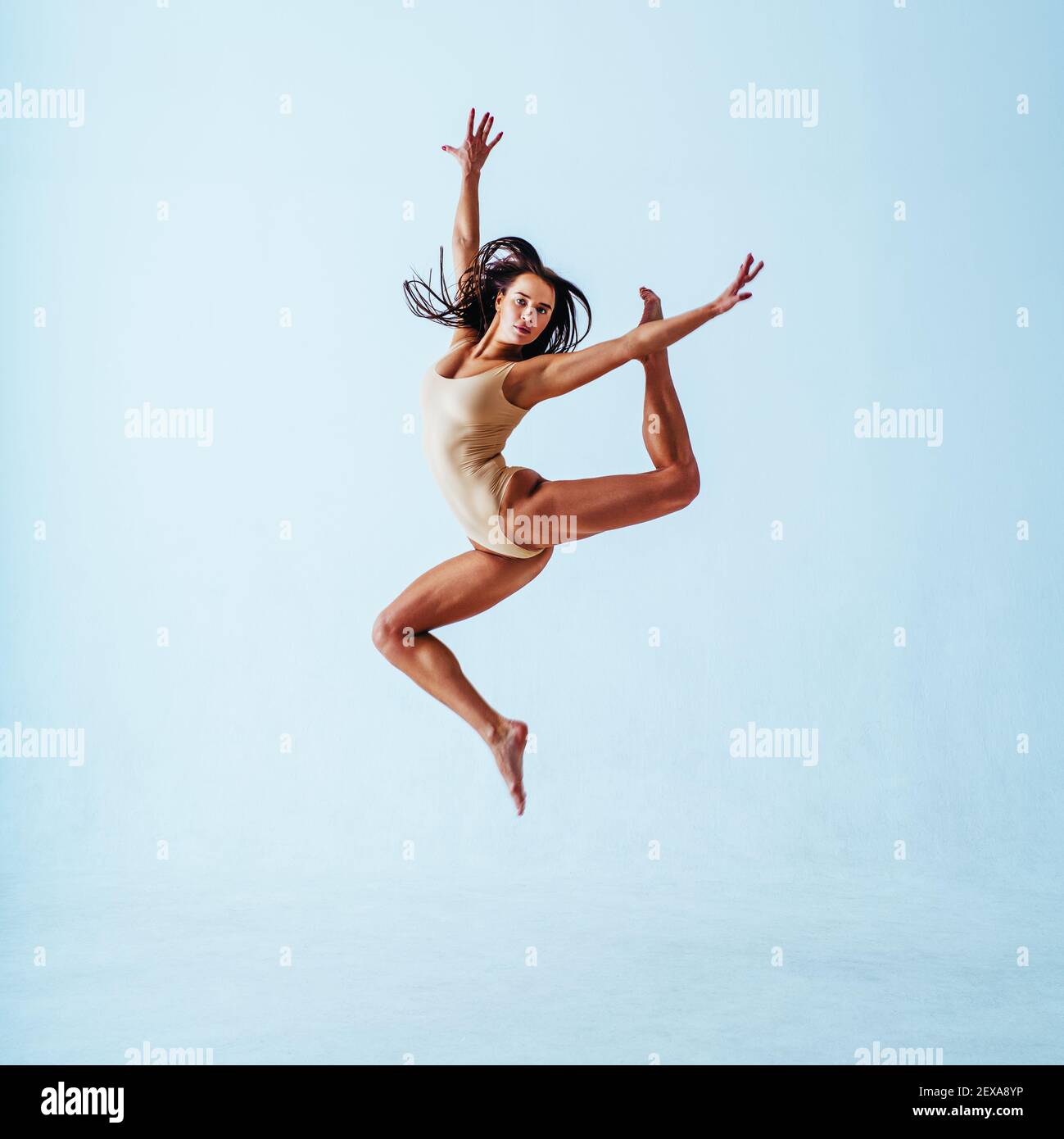 Giovane donna ginnastica saltando con su sfondo bianco Foto Stock