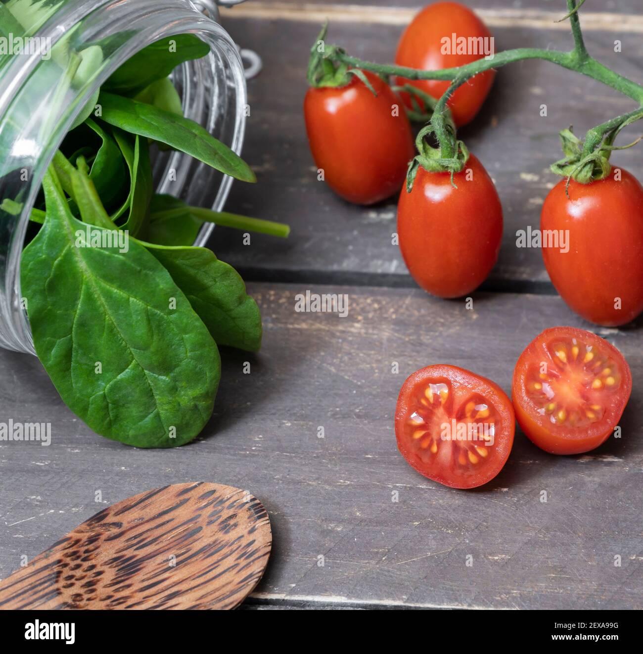 Dieta sana concetto di cibo.Spinach foglie in vaso e pomodori ciliegini su tavola di legno vintage. Foto Stock