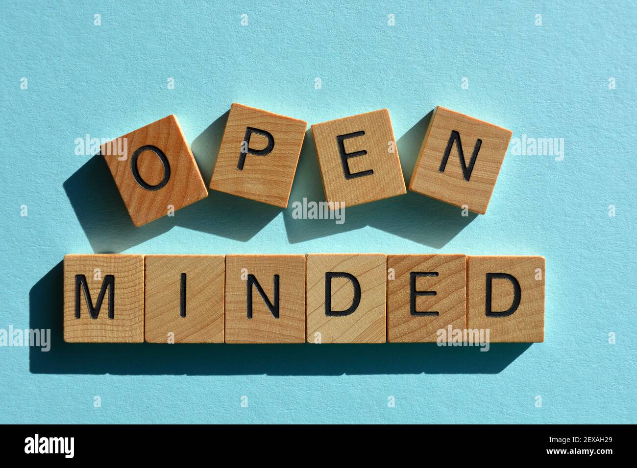 A mente aperta, parole in lettere alfabetiche in legno isolate su sfondo azzurro Foto Stock